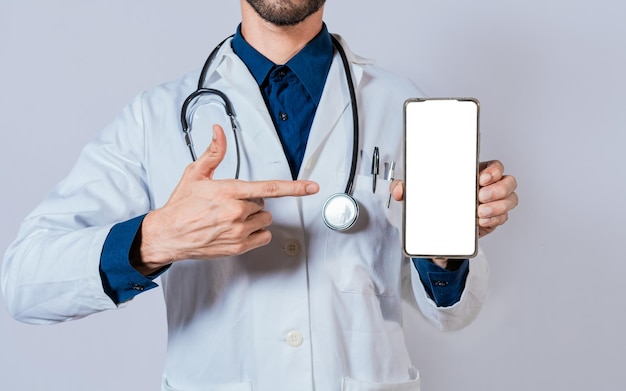 Médico mostrando e apontando para a tela do celular em branco Médico recomendando na tela do celular isolada