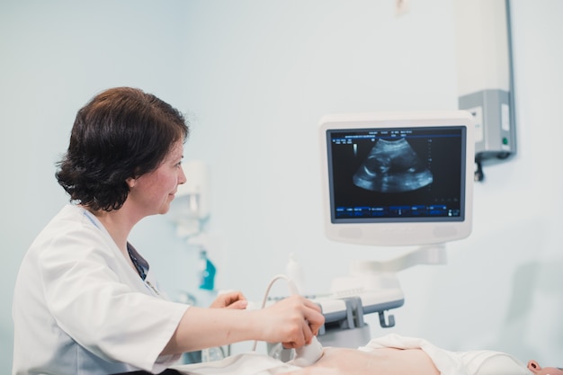 Médico mostrando imagem de ultrassom de bebê no computador para mulher grávida