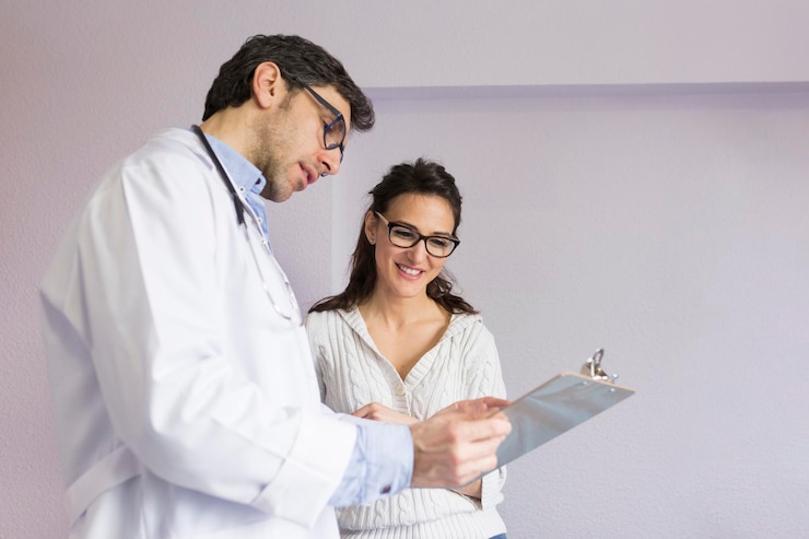 Foto el médico muestra el clipboard a un paciente sonriente de pie en la clínica