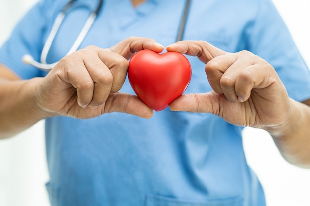 Foto médico de la mujer asiática con corazón rojo en la sala del hospital de enfermería, concepto médico fuerte y saludable