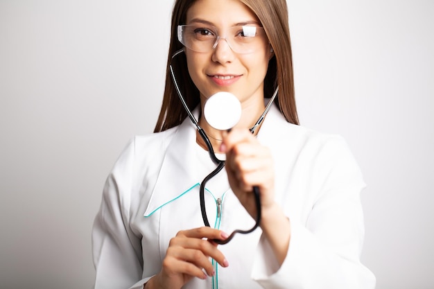 Médico mujer sosteniendo estetoscopio en las manos de cerca