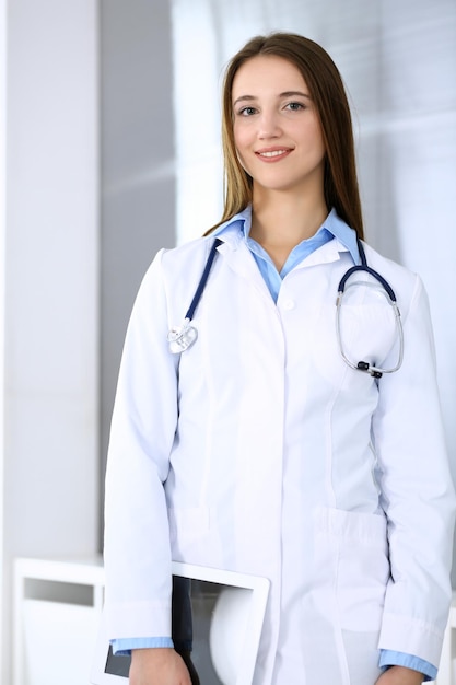Médico mulher feliz e alegre enquanto está no escritório do hospital em destaque o conceito de medicina e saúde