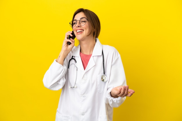 Médico mulher isolada em fundo amarelo, conversando com alguém ao telefone celular