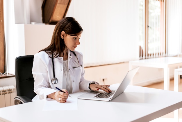 Médico mulher trabalhando no laptop no escritório