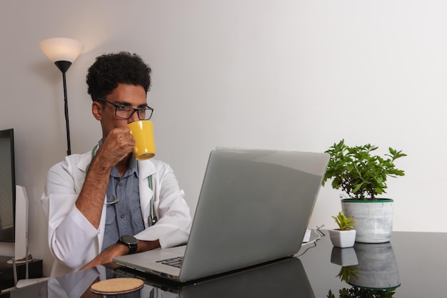 Médico negro brasileño o veterinario trabajando en casa Joven haciendo oficina en casa durante el día en el escritorio con computadora portátil