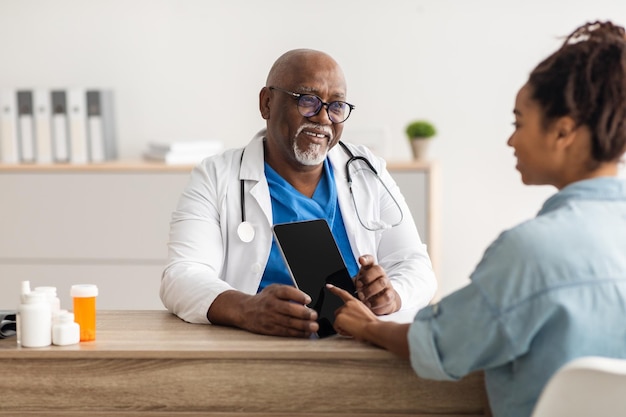 Médico negro experimentado explicando el plan de tratamiento a una paciente