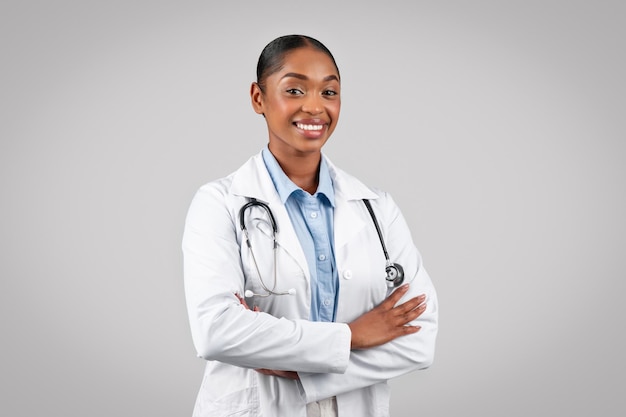 Médico negro profissional alegre sorrindo para a câmera com os braços cruzados