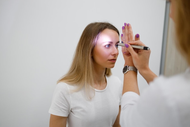 Médico neurólogo que enciende la linterna en los ojos del paciente para ver la reacción de la pupila a la luz en la clínica