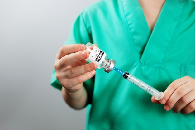 Médico de niña vestida con uniforme azul con jeringa tomando la vacuna contra el coronavirus covid