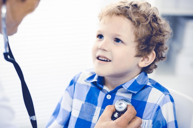 Médico y niño paciente. Médico examinando al niño pequeño. Visita médica regular en la clínica. Concepto de medicina y atención médica.