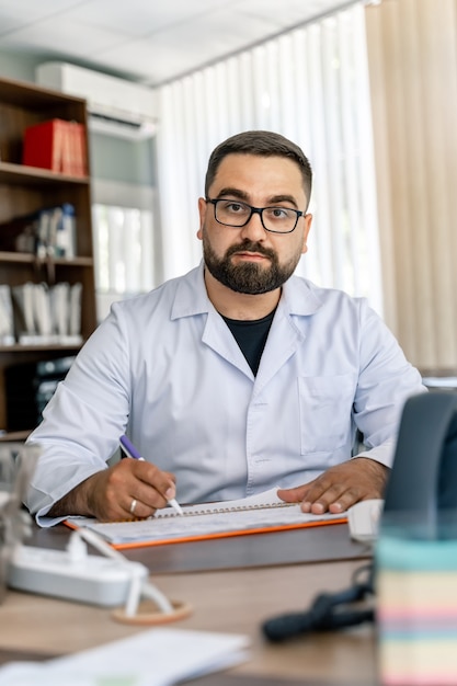 Médico no escritório, sorrindo para a câmera. Fundo de escritório de hospital moderno.