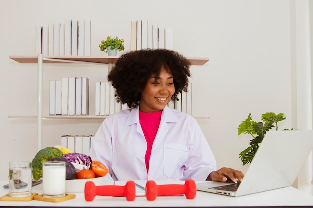 Médico nutricionista afroamericano que se especializa en cocinar se sienta a escribir el teclado de una computadora portátil