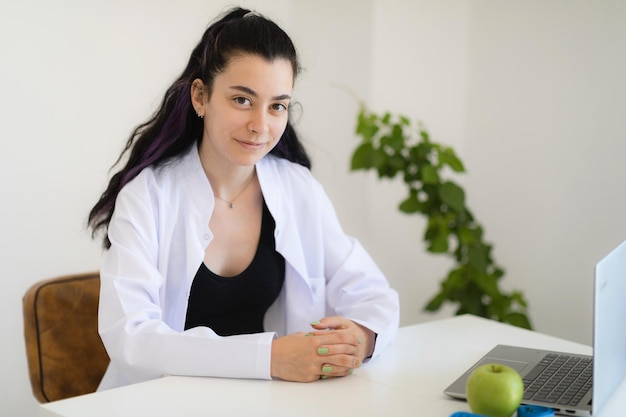 Médico nutricionista sentado em seu gabinete na clínica de emagrecimento sorrindo e olhando para a câmera