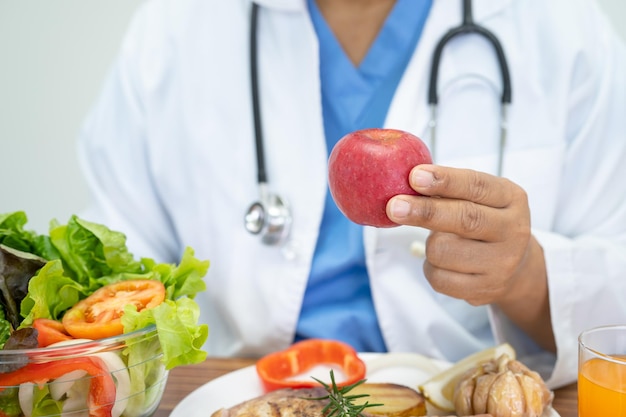 Médico nutricionista con varias verduras frescas saludables para el paciente.