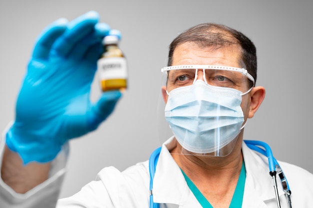 Médico o científico senior hombre sosteniendo el frasco de la vacuna de cerca