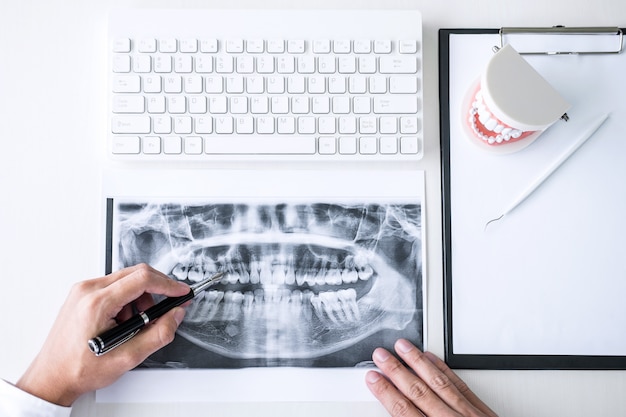 Médico o dentista que trabaja con la radiografía del diente del paciente, el modelo y el equipo utilizado en el tratamiento.