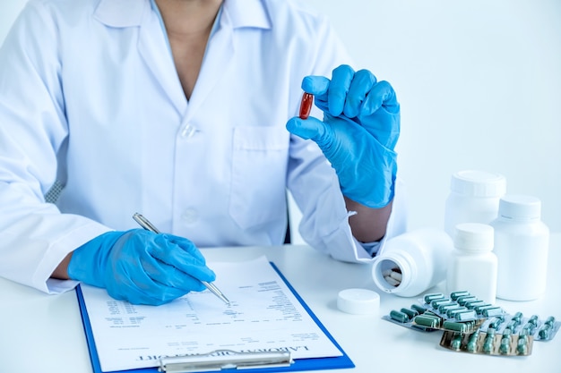 Foto médico o enfermera sosteniendo la píldora de la medicina y escribir la receta en el chequeo médico de la oficina de la farmacia