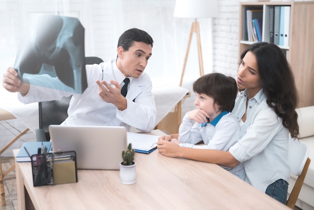 El médico observa la radiografía del niño.