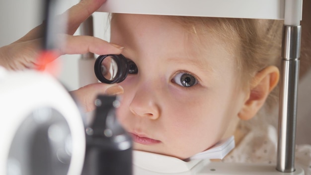 Médico de oftalmología infantil optometrista comprueba la vista de la niña