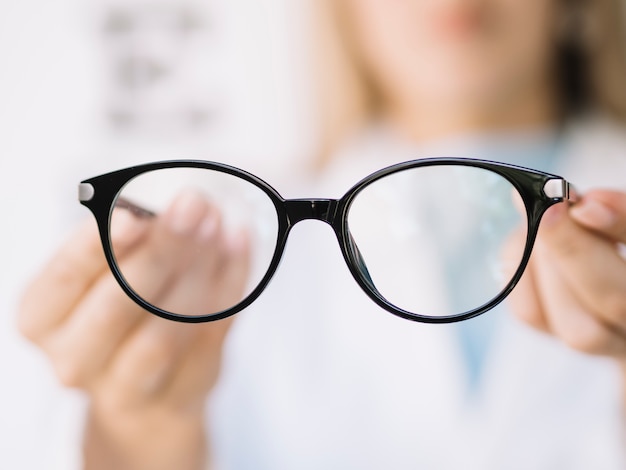 Foto médico oftalmologista de mulheres mostrando o par de óculos de leitura