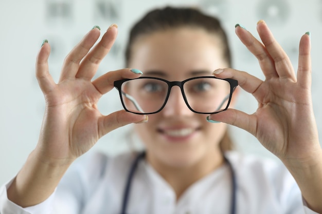 Médico oftalmologista feminino segurando óculos na clínica de oftalmologia