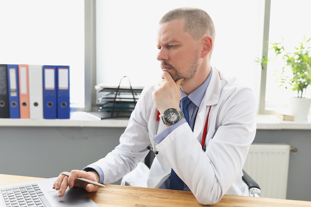 Foto médico olhando para a tela do laptop no escritório