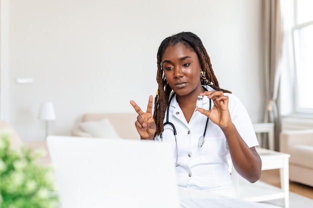 Médico de omán africano hablando en línea con un paciente haciendo una videollamada mirando a la cámara mujer joven con uniforme blanco con estetoscopio hablando consultoría y concepto de terapia