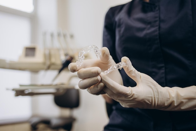 Médico ortodontista em luvas colocando aparelho transparente invisível de silicone nos dentes da mulher na visão de close-up da boca da clínica do dentista Corrigindo o tratamento dos dentes e a cura na odontologia