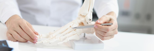 Foto médico ortopédico mostra modelo de pés de plástico humano analisando cada osso e dedo do pé