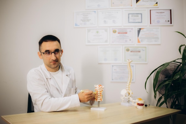 Médico ortopédico mostrando el modelo anatómico de la columna vertebral