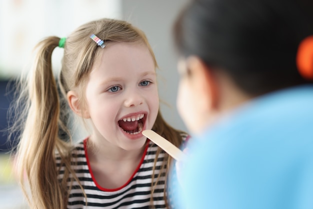 Médico otorrinolaringólogo examina el dolor de garganta niña en la clínica