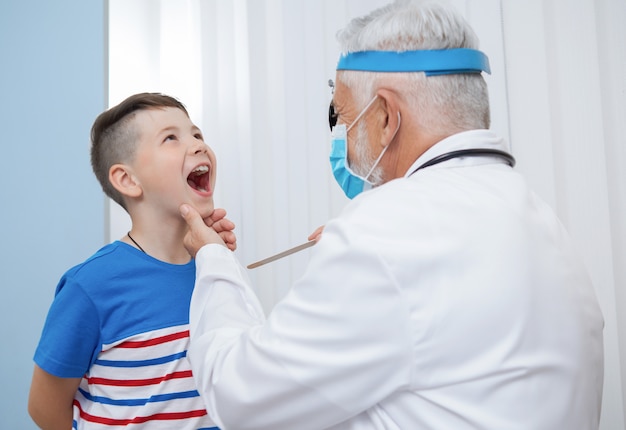 Médico otorrinolaringólogo que examina la garganta del niño.