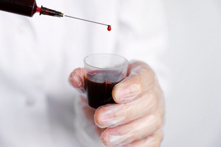 Foto médico ou cientista de laboratório em equipamento de proteção individual segurando uma seringa cheia de sangue
