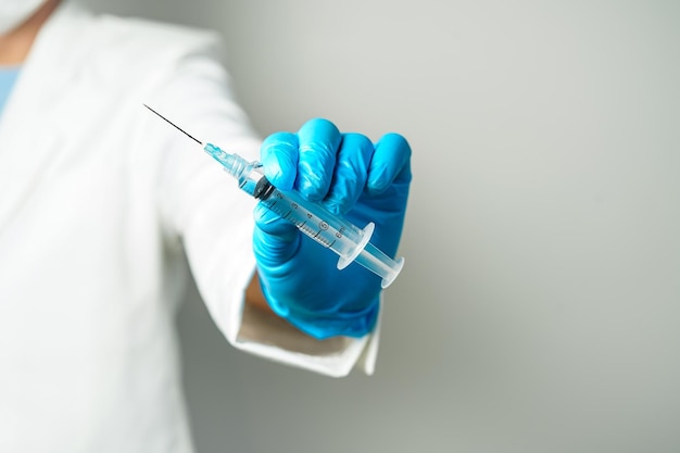 médico ou cientista segurando uma seringa com luvas azuis