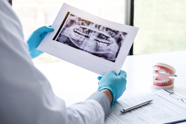 Médico ou dentista segurando e olhando para raio x dental