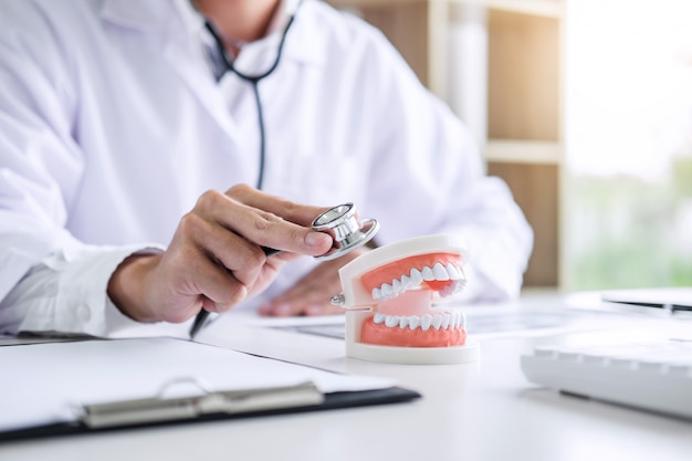 médico ou dentista, verificando a doença de dentes em modelo odontológico e equipamentos utilizados no tratamento de dental