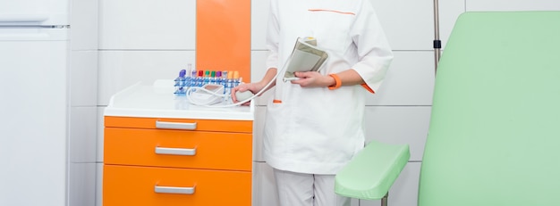 Médico ou enfermeiro segurando o medidor digital de pressão arterial no quarto de hospital moderno