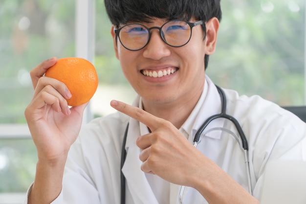 Médico ou nutricionista, segure a laranja e aponte o dedo para a laranja.