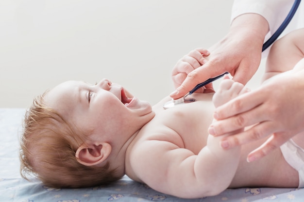 Foto médico ouve criança pequena com estetoscópio