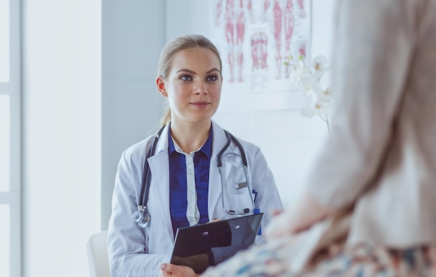 Médico y paciente discutiendo algo mientras están sentados en la mesa. Concepto de medicina y atención de la salud.