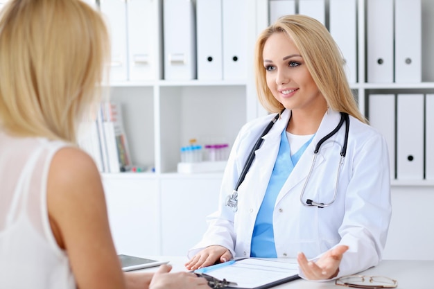 Médico y paciente discutiendo algo mientras están sentados en la mesa. Concepto de medicina y atención de la salud.