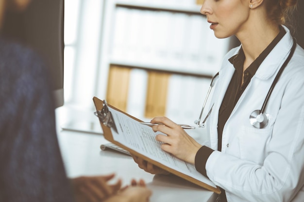 Médico y paciente discutiendo el examen de salud actual mientras están sentados en la clínica. Perfecto servicio médico en el hospital.