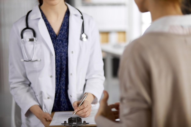 Médico y paciente discutiendo el examen de salud actual mientras están sentados en la clínica. Servicio médico perfecto en el hospital. Concepto de medicina.