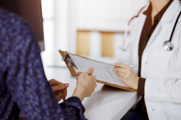 Médico y paciente discutiendo el examen de salud actual mientras están sentados en una clínica soleada. Perfecto servicio médico en el hospital.