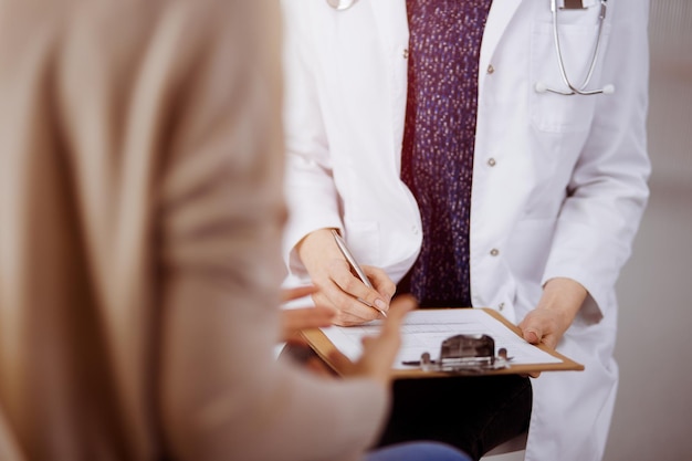 Médico y paciente discutiendo el examen de salud actual mientras están sentados en una clínica soleada. Perfecto servicio médico en el hospital.