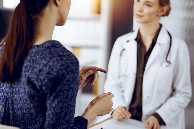 Médico y paciente discutiendo el examen de salud actual mientras están sentados en la soleada clínica Concepto de medicina