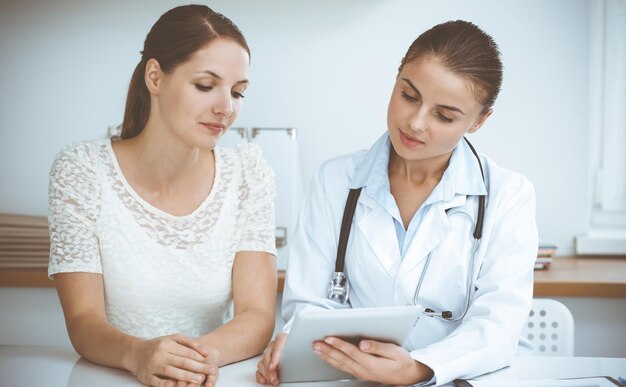 Foto el médico y el paciente están sentados y discutiendo los resultados de los exámenes de salud mientras usan una tableta. conceptos de salud, medicina y buenas noticias.