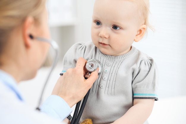 Médico y paciente en el hospital. Una niña vestida de gris está siendo examinada por un médico con estetoscopio. concepto de medicina.