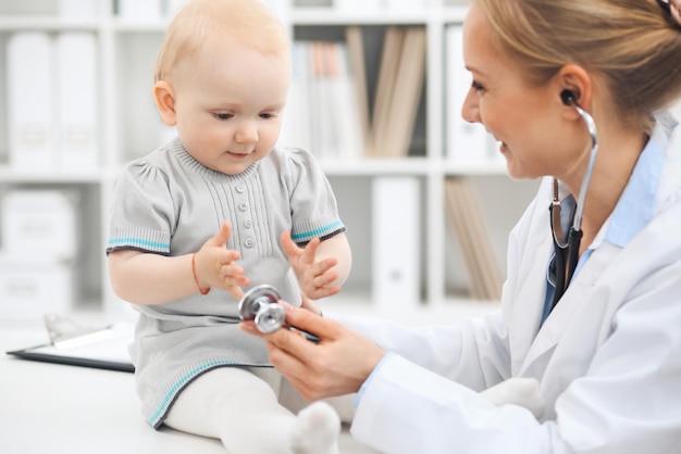 Médico y paciente en el hospital. Una niña vestida de gris está siendo examinada por un médico con estetoscopio. concepto de medicina.