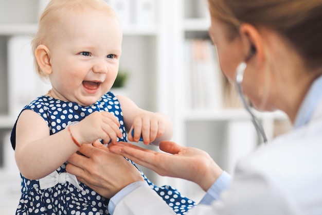 Médico y paciente en el hospital. Una niña vestida con un vestido azul oscuro está siendo examinada por un médico con estetoscopio. Concepto de medicina y salud.